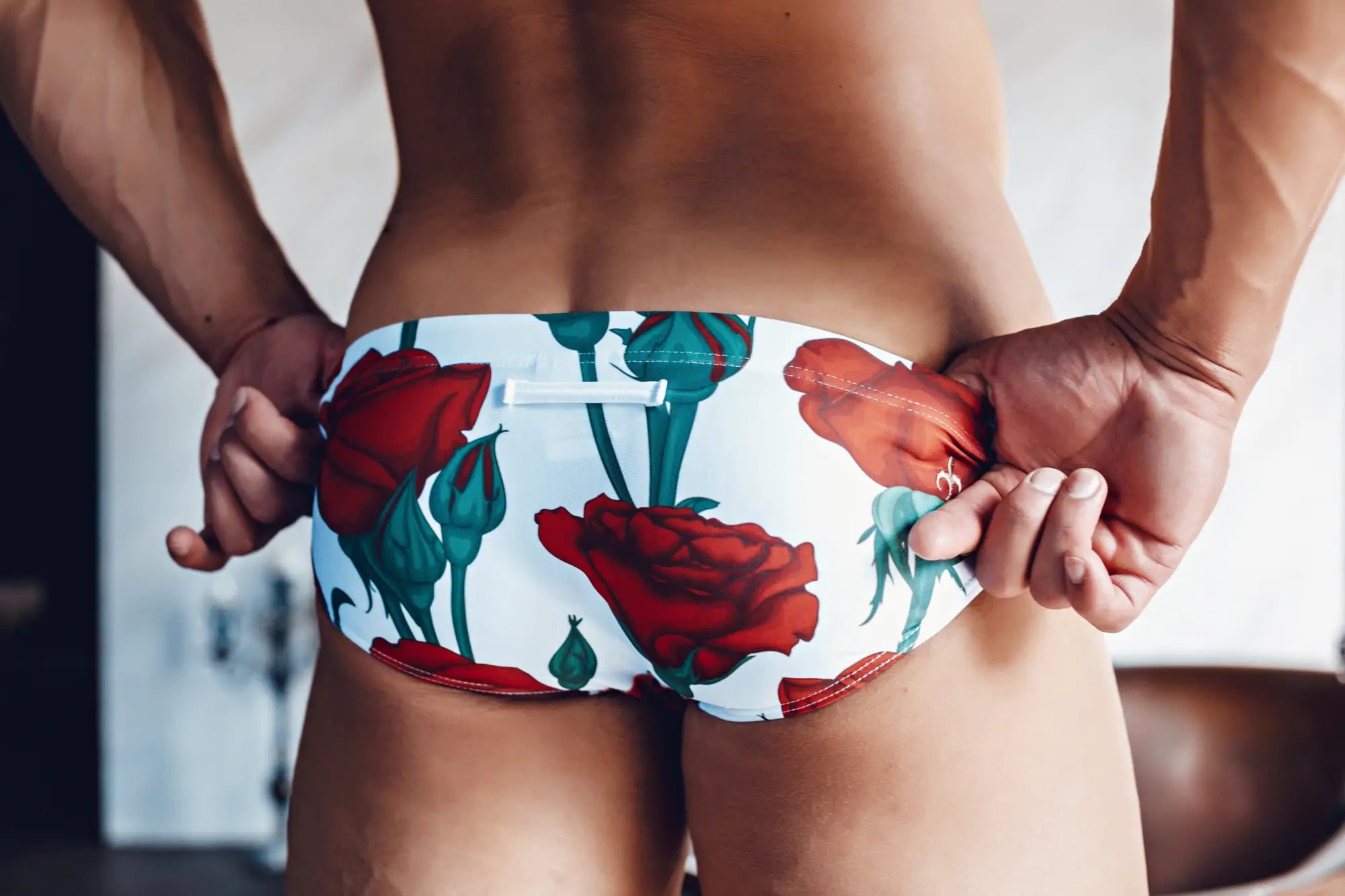 White swim trunks with vibrant red rose and green stem floral pattern from marcuse amour bikini swimwear collection