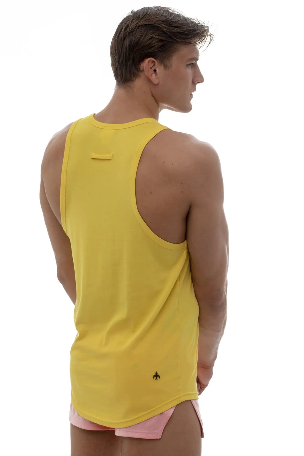 Back view of marcuse avalon yellow sleeveless athletic tank top with rounded neckline and subtle black logo