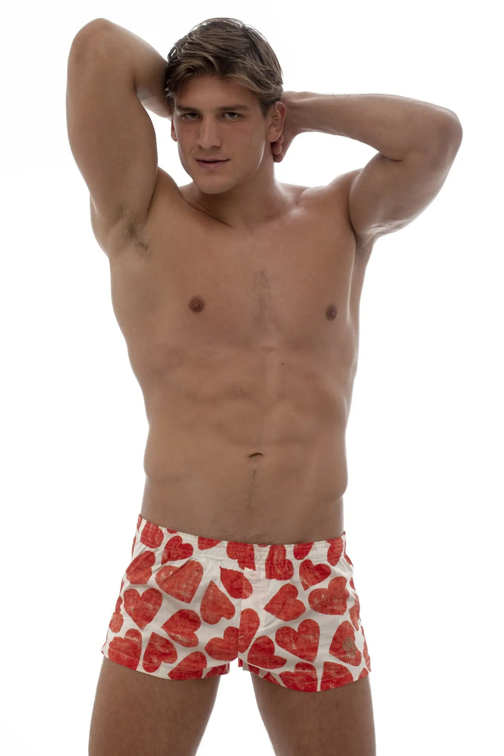 Red heart-patterned swim trunks by marcuse featuring boxer underwear style for men in vibrant red color