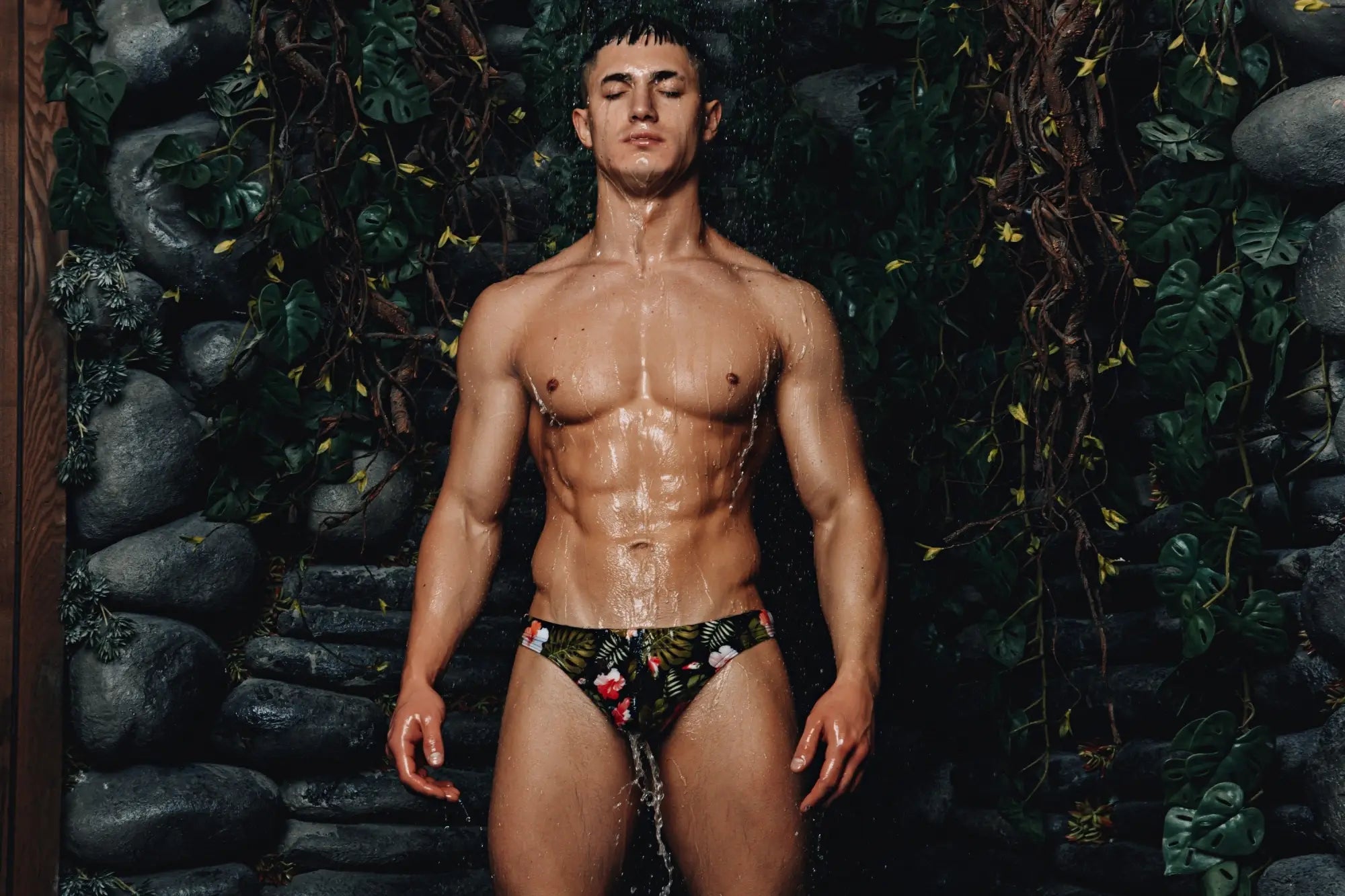 Marcuse Forrest thong swimwear featuring vibrant red and green tropical floral pattern on dark fabric