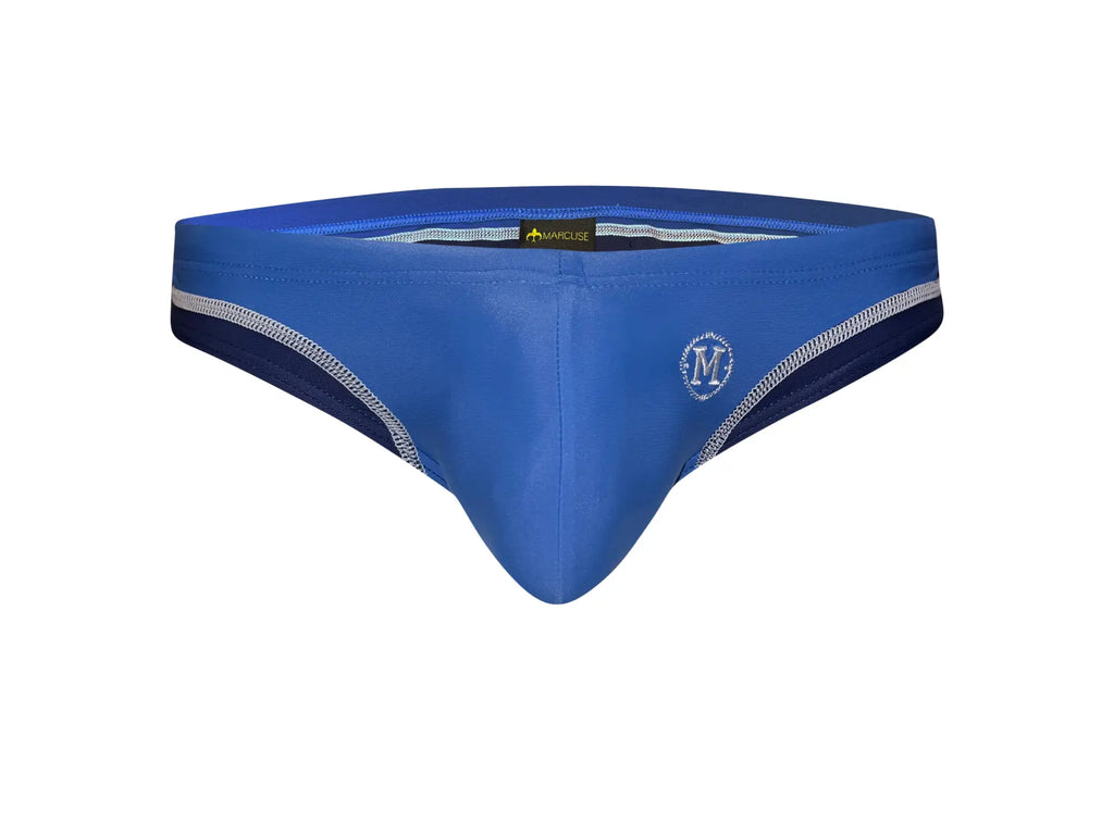 Blue men’s swim trunks with navy side panels and white stitching details from Marcuse Joyeux bikini swimwear collection