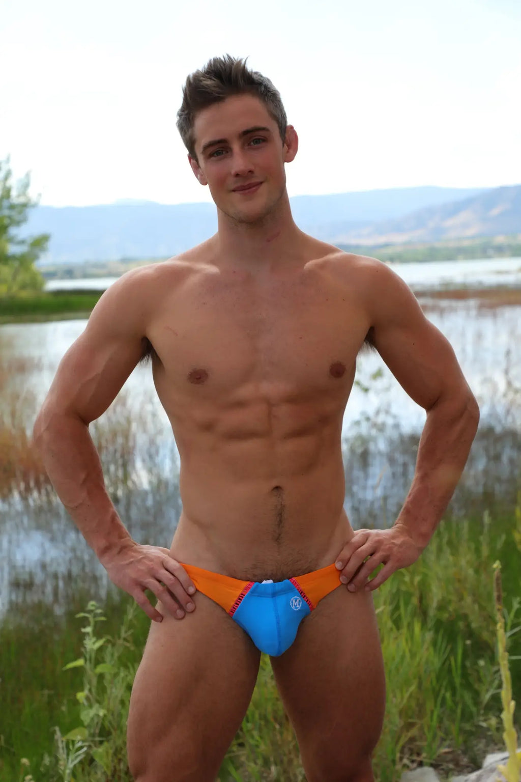 Marcuse Jupiter bikini swimwear featuring blue and orange swim trunks with a small logo on the front