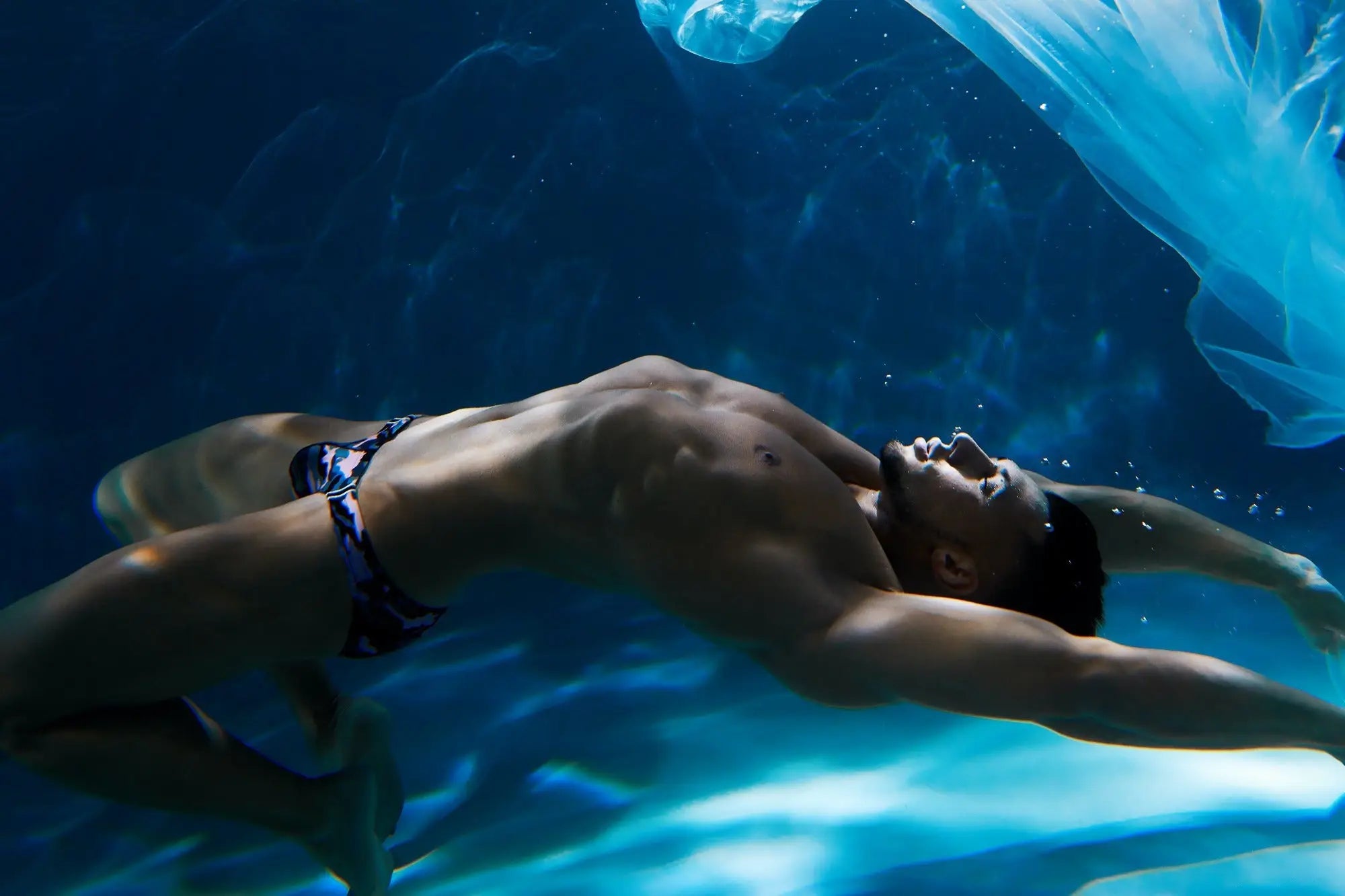 A man wearing dark blue and black patterned Marcuse Master bikini swimwear underwater