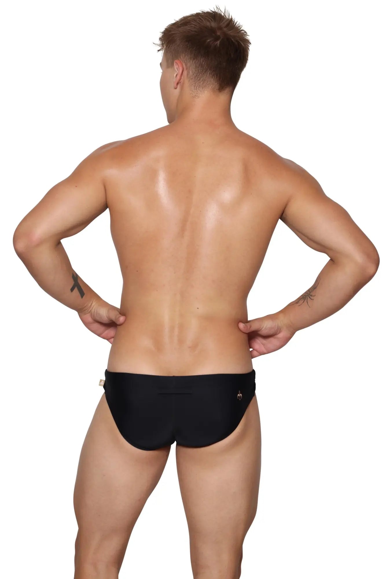 Black brief-style swim trunks with a small metallic logo on the right hip from marcuse mecha bikini swimwear