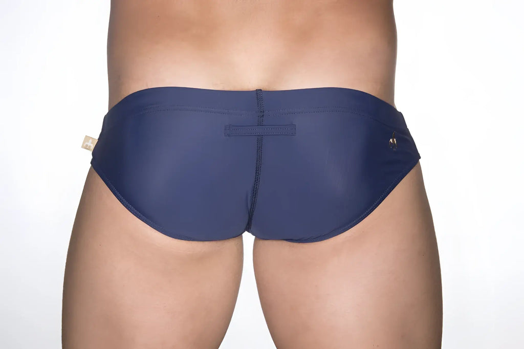 Navy blue marcuse patrol bikini swimwear trunks with subtle seam detail and small gold tone logo on the side