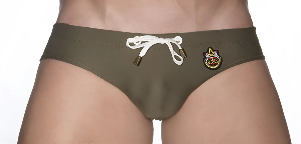 Olive green marcuse patrol bikini swimwear trunks with white drawstring and colorful embroidered side patch