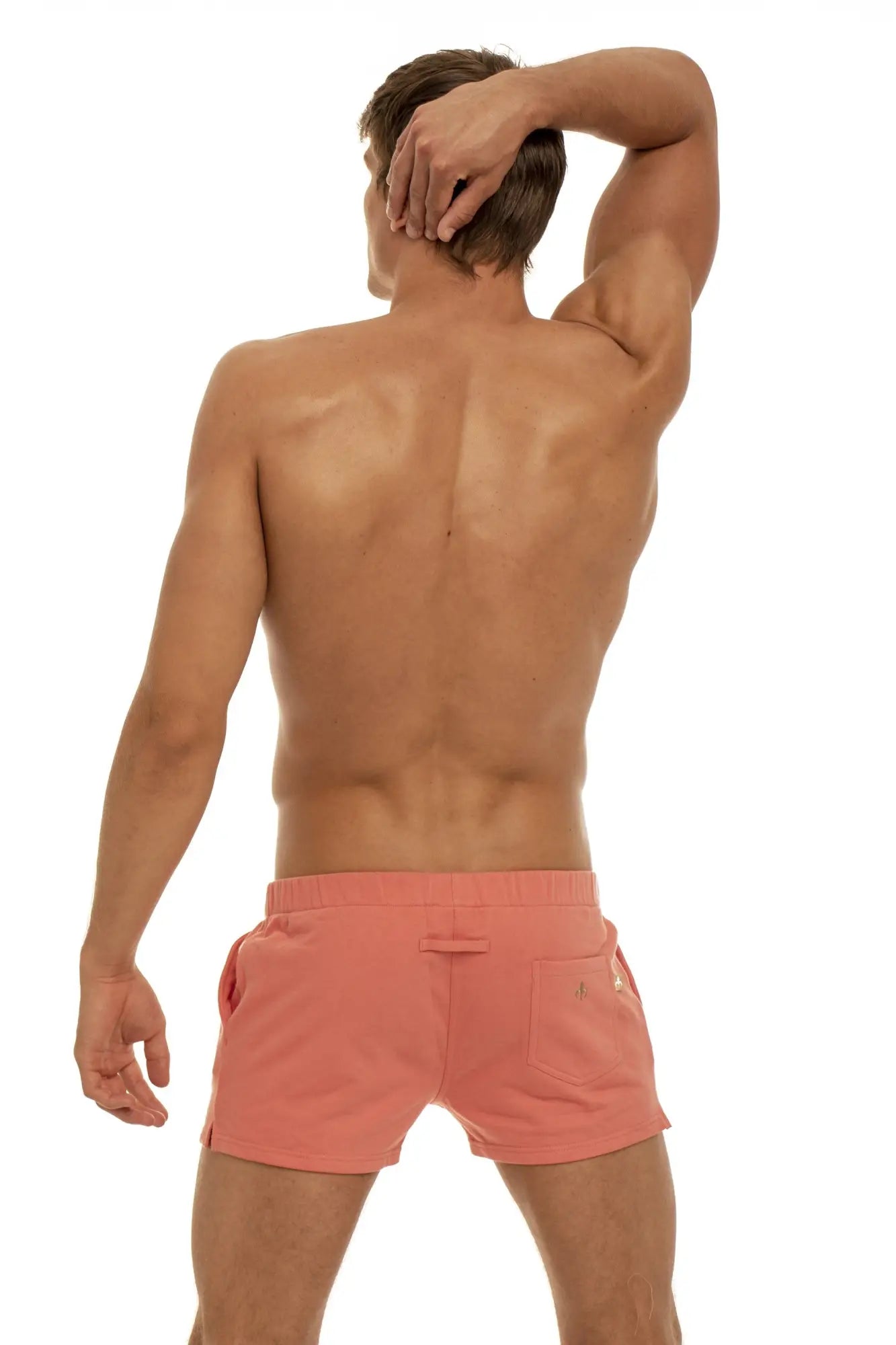 Marcuse physical coral-colored athletic shorts with sleek modern design and subtle branding on the side pocket