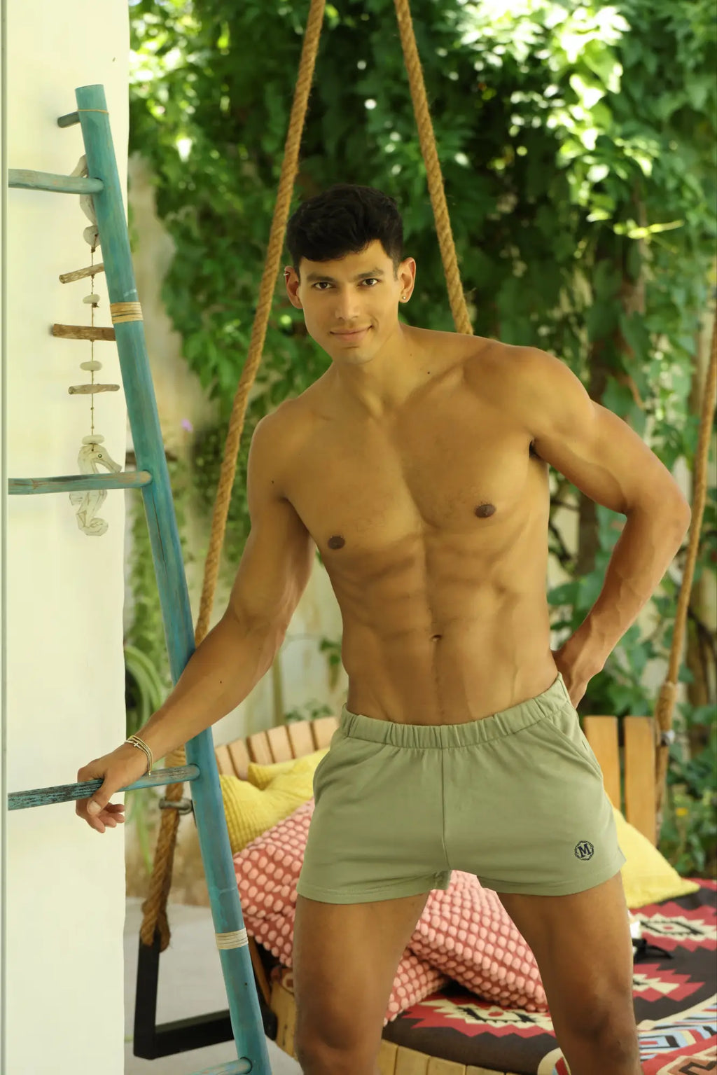 Man wearing light green marcuse physical shorts with elastic waist and small black logo on lower right leg