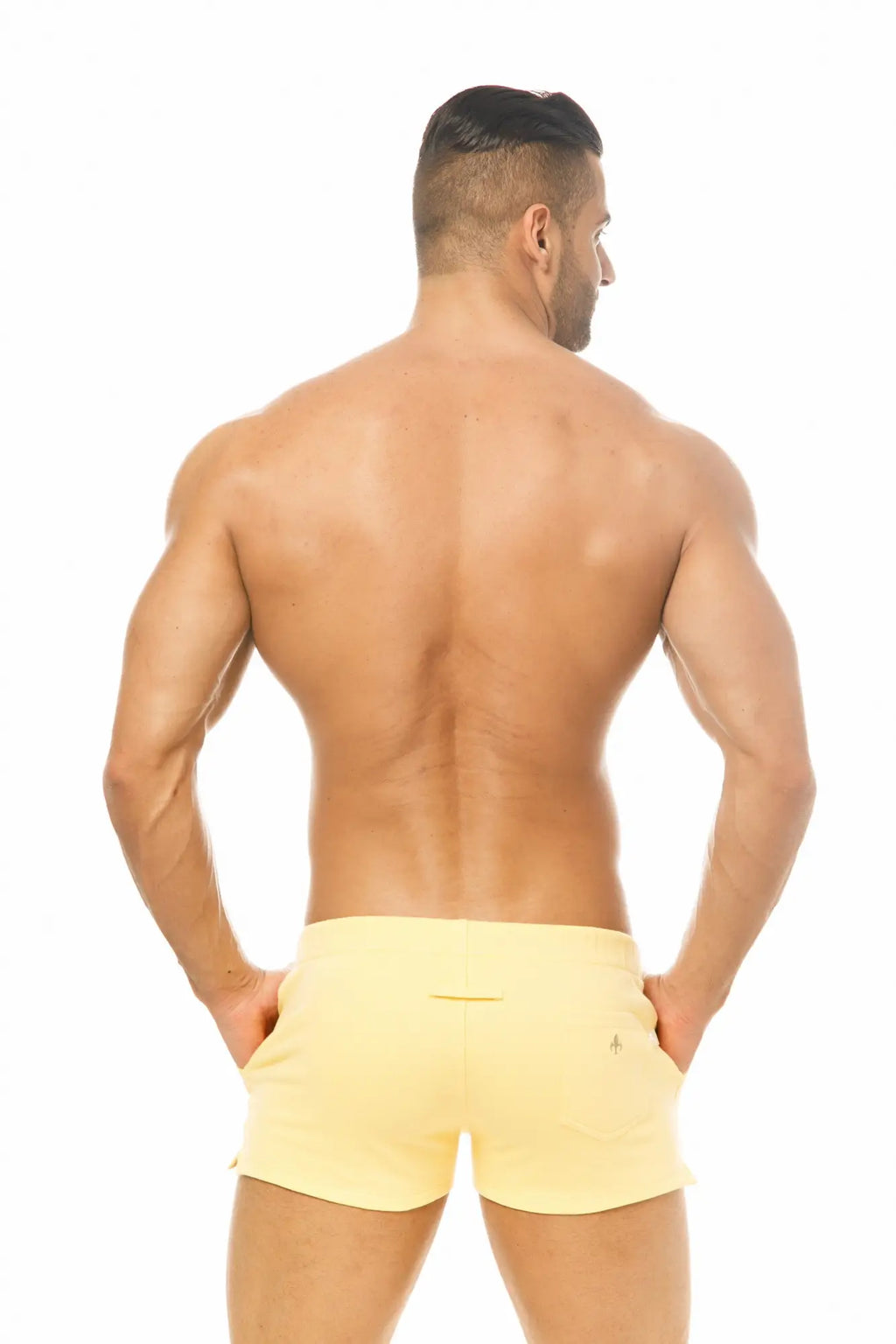 A pair of bright yellow marcuse physical athletic shorts showing the back side with a small logo on the waistband