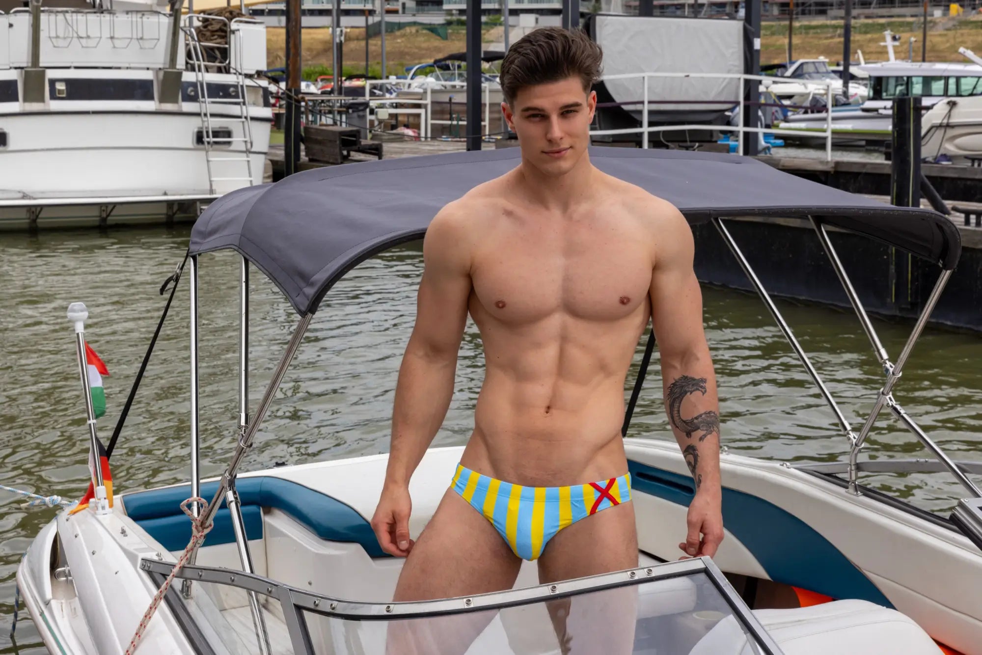 Marcuse promenade bikini swimwear featuring brightly striped yellow and blue swim trunks with a red x design
