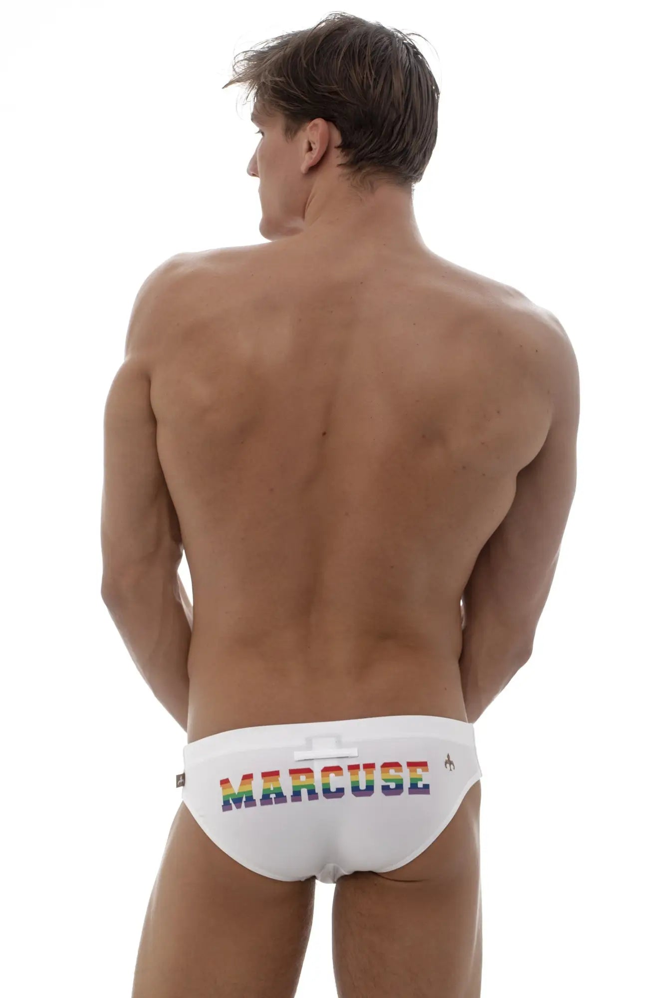 White marcuse swim trunks with rainbow-colored marcuse logo across front from marcuse proud bikini swimwear collection