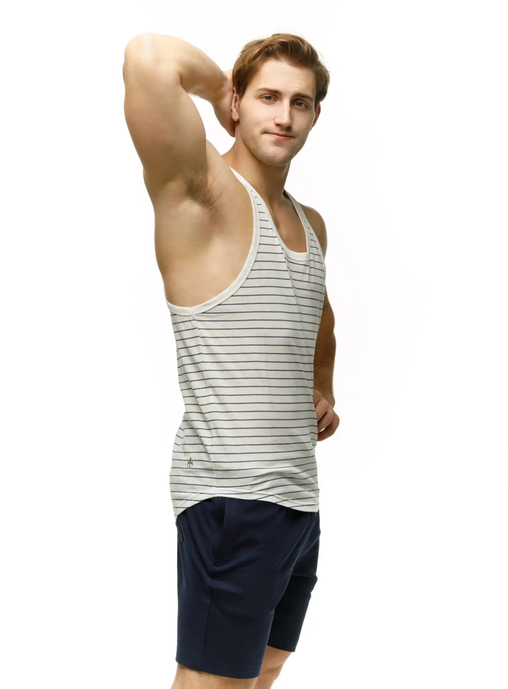 A man wearing a marcuse somer tank top with thin navy blue stripes and dark navy shorts standing front view