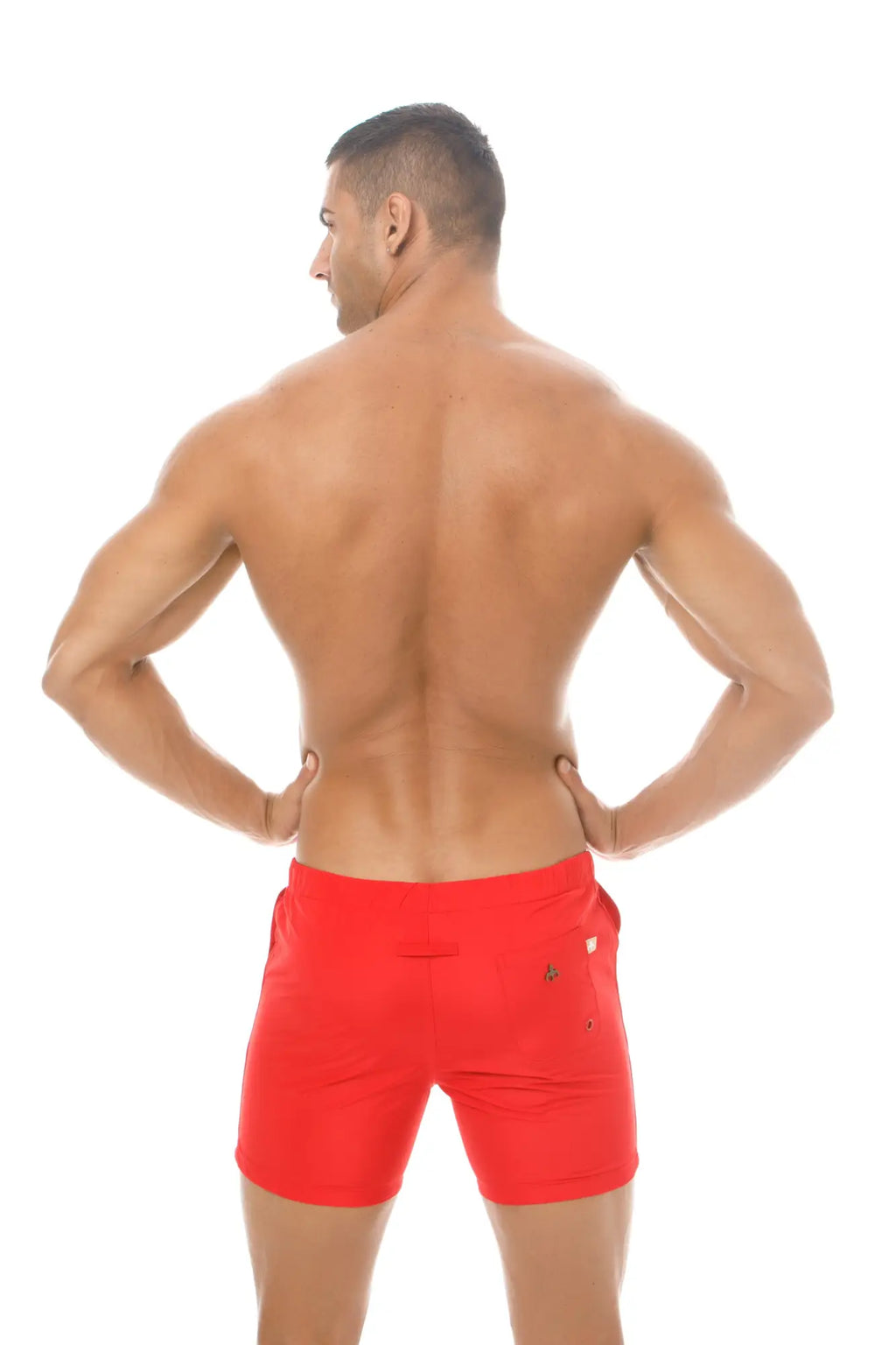 Back view of red marcuse spectrum athletic shorts with a small gold logo on the back pocket