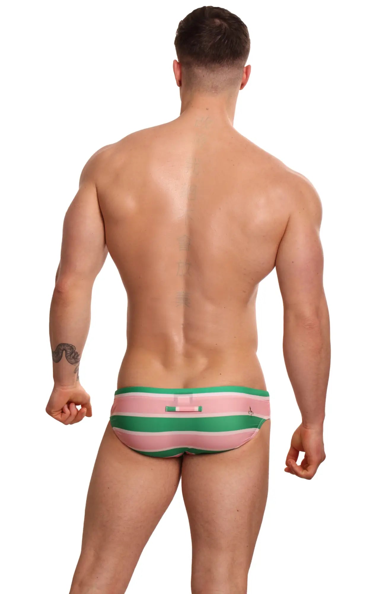 Back view of marcuse traverse bikini swimwear pink and green striped swim trunks with a small pink tab