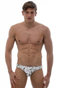 A pair of marcuse utopia bikini swimwear men’s swim trunks with bold white daisy pattern on dark gray fabric