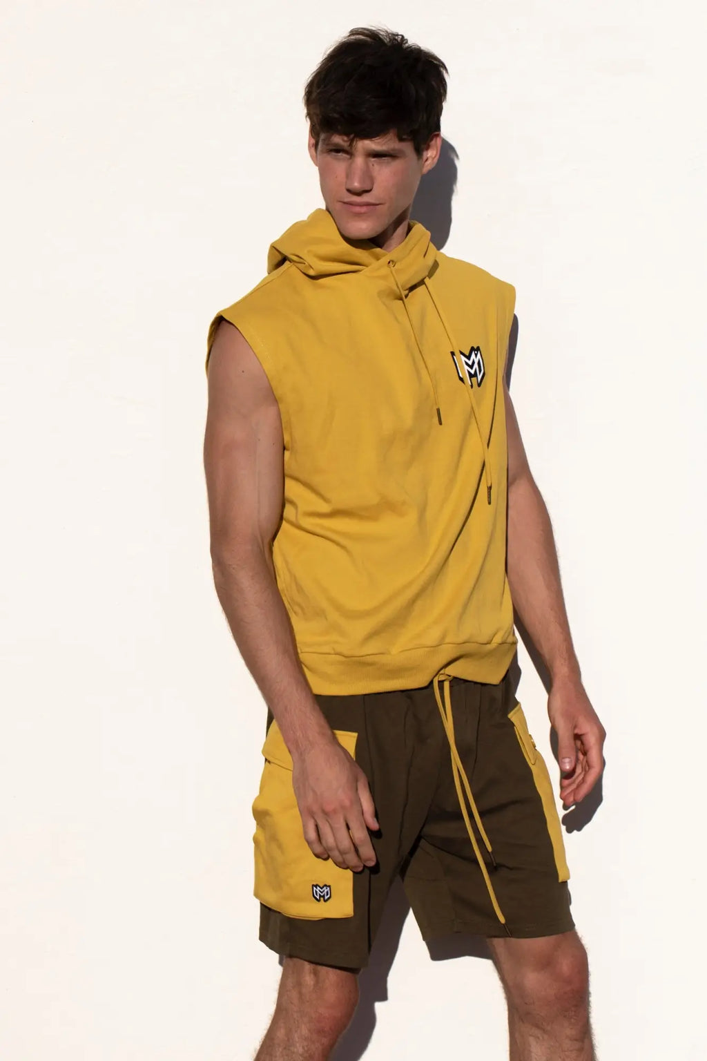 Marcuse Zaiden yellow sleeveless hoodie with black logo paired with matching yellow-trimmed dark green shorts