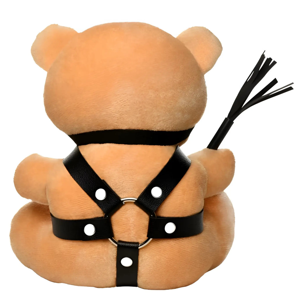 Tan plush bear wearing black leather harness with white snaps holding black whip in master series bdsm teddy bear plushy