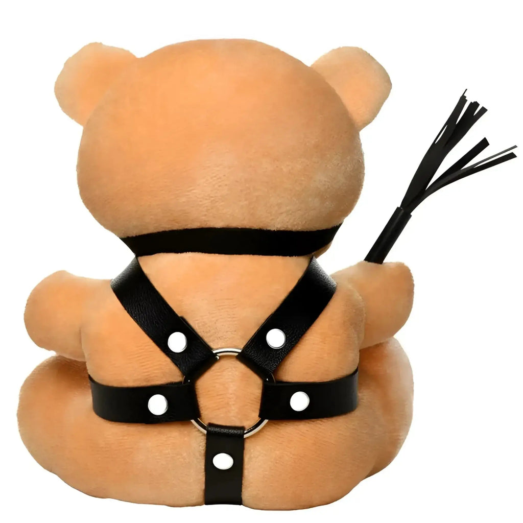 Tan plush bear wearing black leather harness with white snaps holding black whip in master series bdsm teddy bear plushy