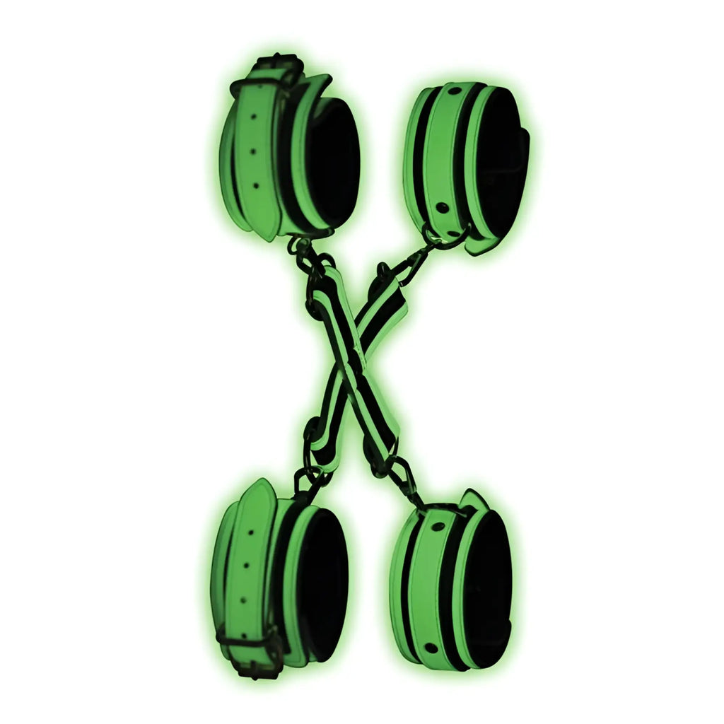 Glowing green and black leather handcuffs with chains forming an x-shape from master series kink in the dark set