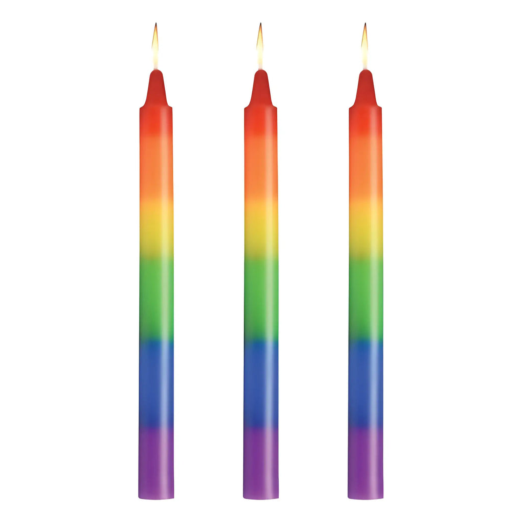 Three lit rainbow-colored taper candles with smooth gradient hues from red to purple master series pride candles 3 pc