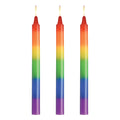 Three lit rainbow-colored taper candles with smooth gradient hues from red to purple master series pride candles 3 pc