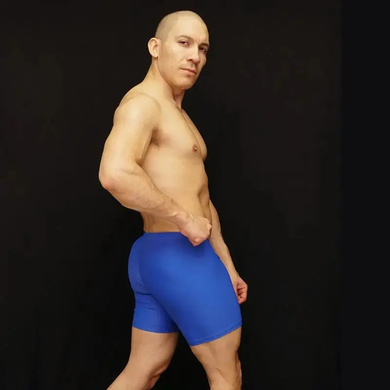 Blue athletic biker shorts made of stretchy material shown on a model from the side by Arroyman.