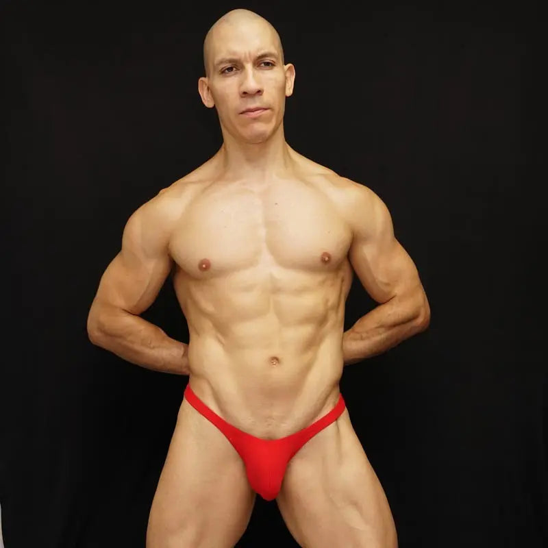 Red micro bikini underwear by Arroyman featuring a minimal design worn by a model against a black background.