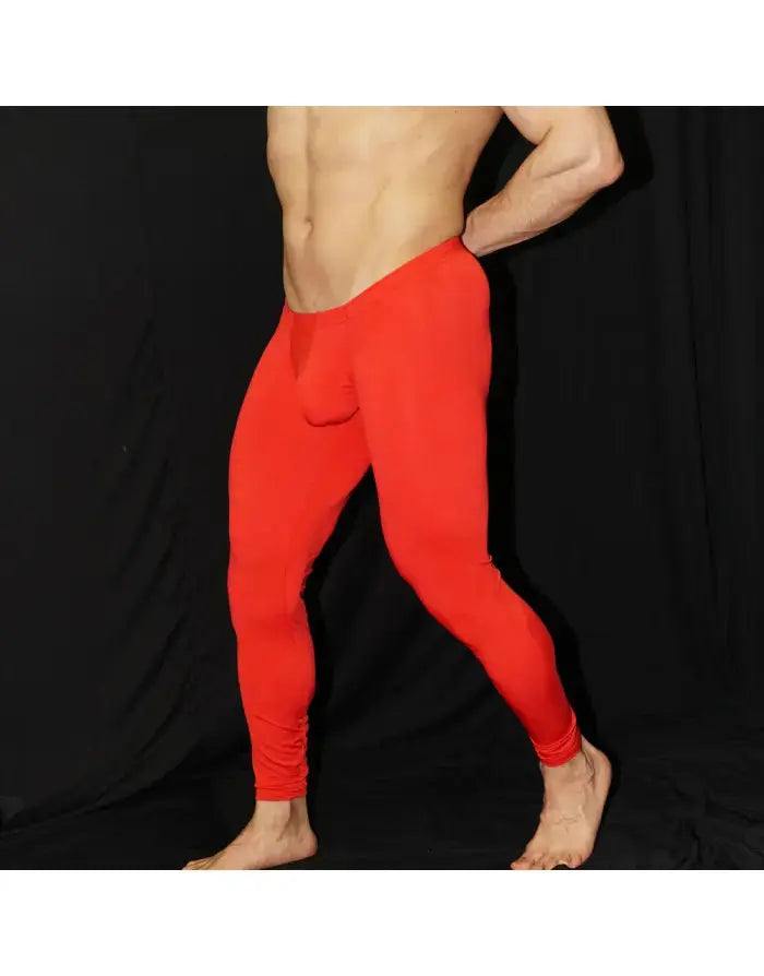 Red men's tights made of stretchy material featuring a bulge-enhancing design shown on a model against a dark background by Arroyman