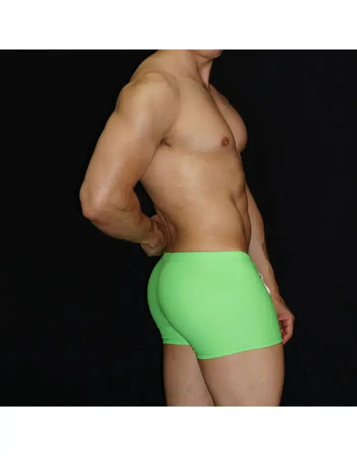 Fluor green square cut boxer swimwear by Arroyman featuring a snug fit and smooth fabric modeled from the side.