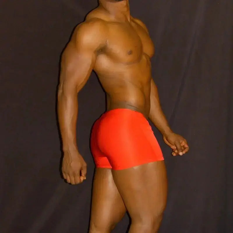 Red square-cut swim trunks by Arroyman featuring a snug fit and smooth fabric shown on a model from the side.