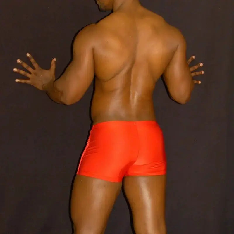 Red square-cut swim trunks by Arroyman featuring a snug fit and smooth fabric shown on a model from the back.