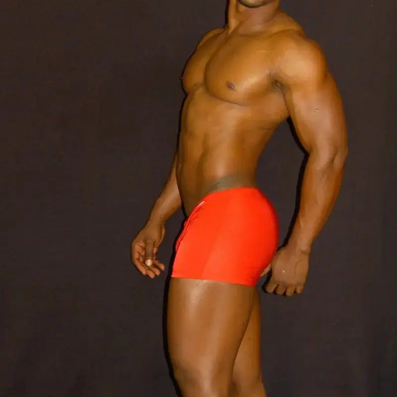 Red square-cut swim shorts by Arroyman featuring a fitted design and smooth material shown on a model.