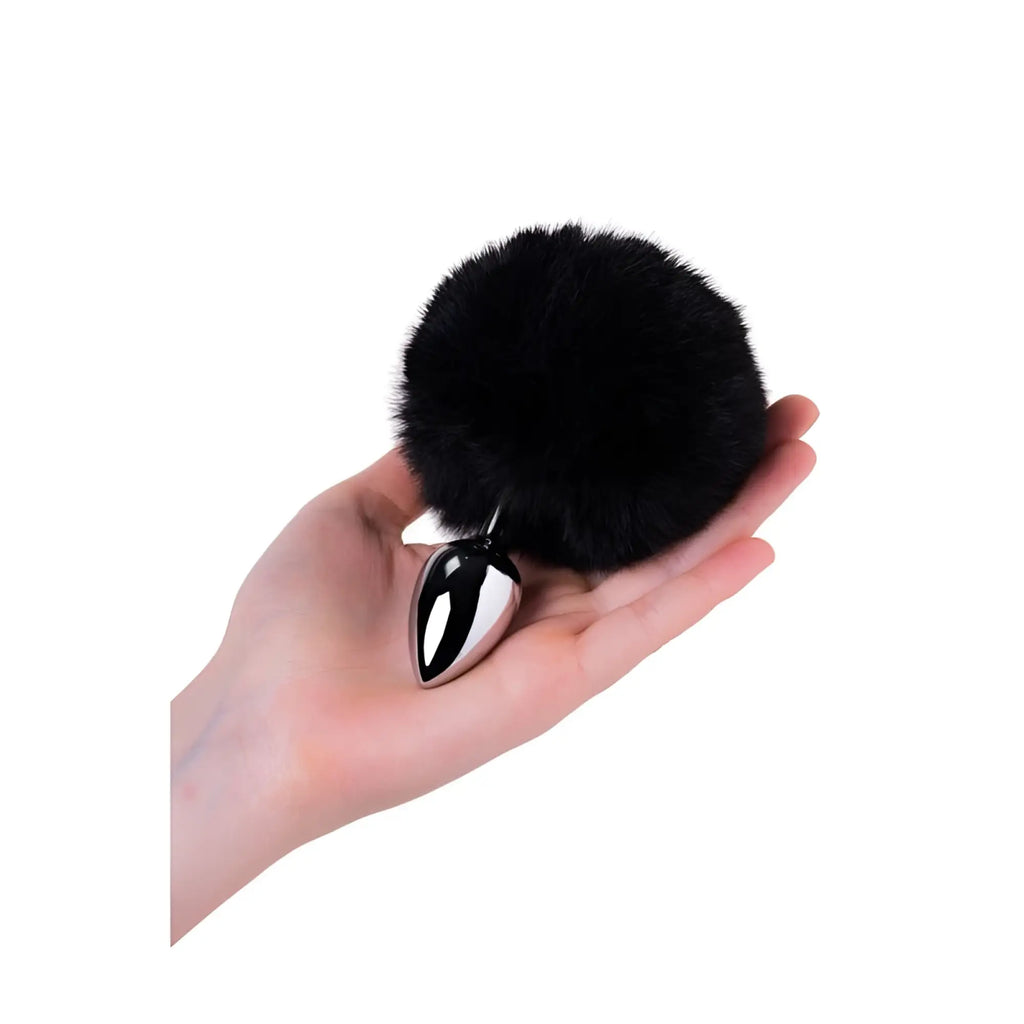 Metal silver small anal plug with polished finish and sleek black fur pom-pom attached shown from the back side