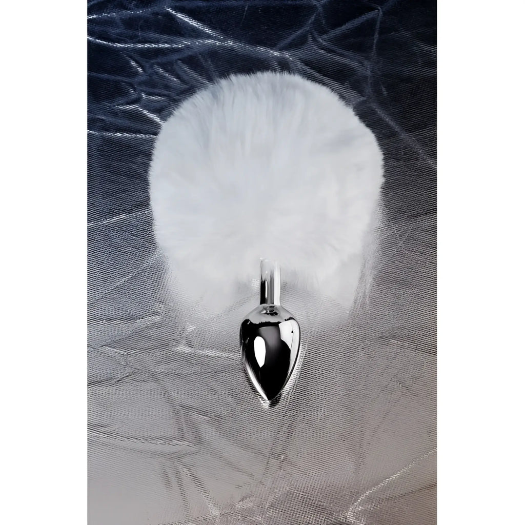 A sleek silver-toned metal anal plug small with a plush white faux fur pom-pom tail attached to the top