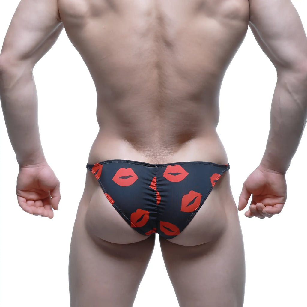Black swim trunks by MetroMaleWear featuring a bold red lipstick print pattern for stylish beachwear