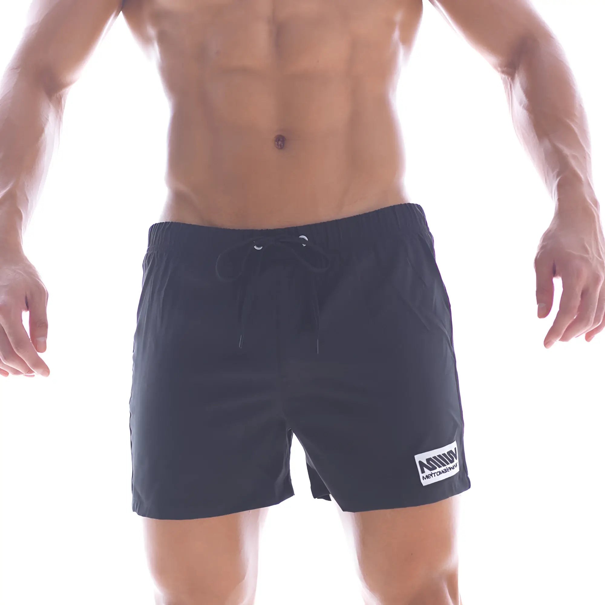 Black athletic MetroMaleWear flexible swim trunks with drawstring waistband and white logo patch on lower right leg