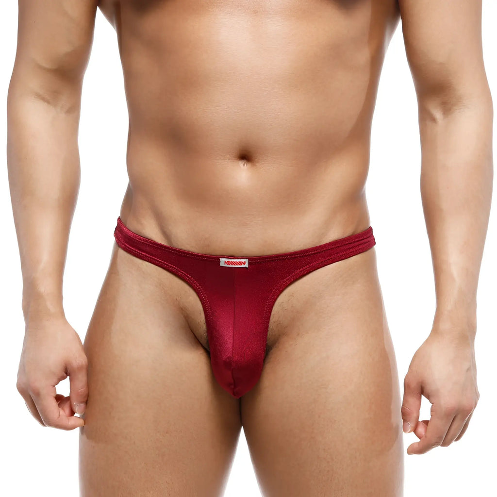 A sleek deep red metroMalewear fria men’s thong made of smooth stretchy fabric with a white brand tag at the waistband