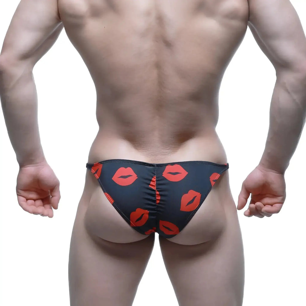 Black swim trunks by MetroMaleWear featuring a bold red lipstick print pattern for stylish beachwear