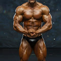 A muscular male bodybuilder wearing a sleek black latex brief metro musclwear basic competition suit leather 4974-74