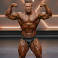 A muscular man wearing black leather MetroMaleWear MetroMuscleWear chain competition briefs with silver chain detail