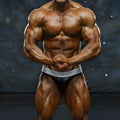 A muscular male bodybuilder wearing black and silver MetroMaleWear DIY competition briefs for muscle contests