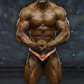 A muscular man wearing black and copper-colored MetroMaleWear MetroMuscleWear mark competition briefs