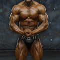 A muscular bodybuilder wearing black competition briefs with a silver white decorative belt from MetroMaleWear