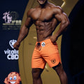 Orange MetroMaleWear MetroMuscleWear physique board short with black drawstring and small shield logo on lower right leg