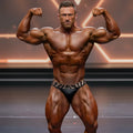 A muscular man wearing black briefs with a zebra-striped waistband showcasing the MetroMaleWear Zebra Competition Suit 4974-30