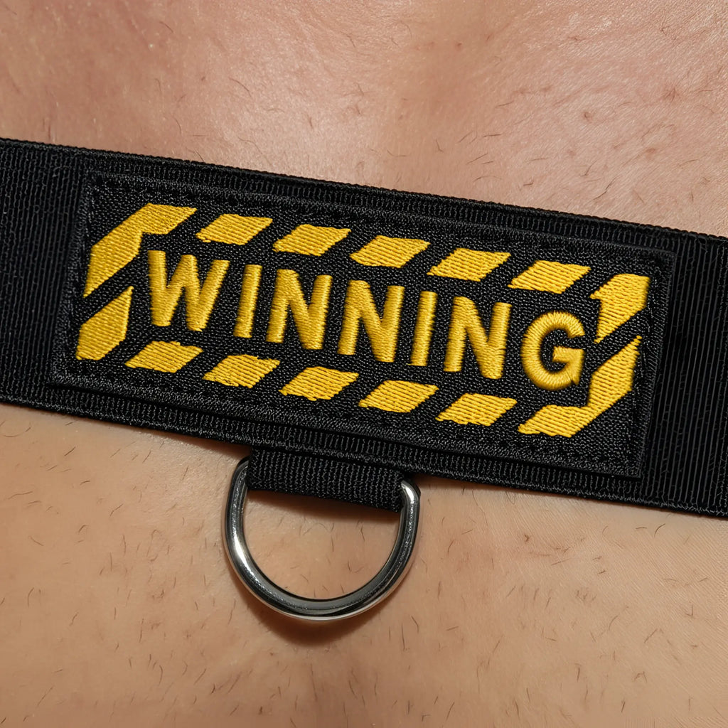 Black fabric strap body harness with yellow winning embroidery caution stripe and silver metal d ring by metromalewear
