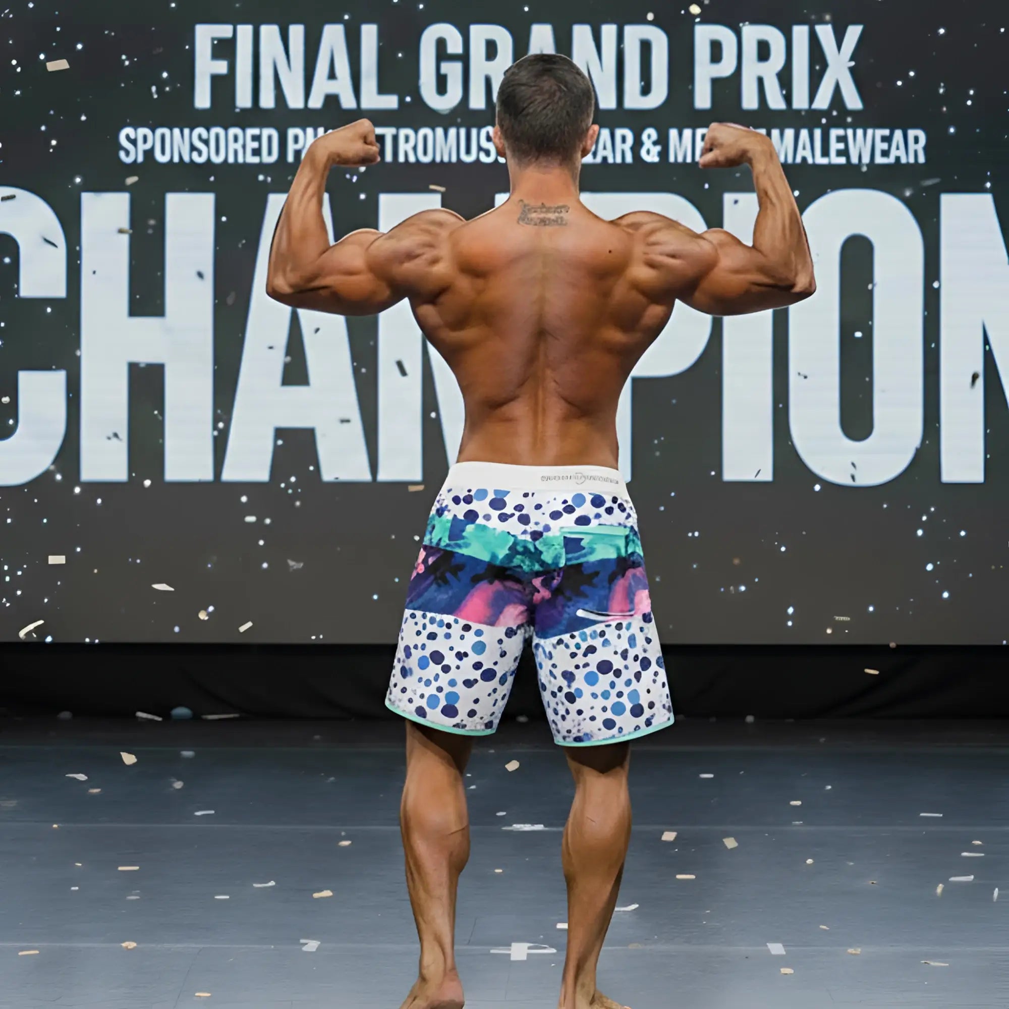 A man wearing metromalewear metromusclewear bubble physique board shorts with vibrant blue pink and teal abstract patterns
