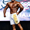 White MetroMaleWear MetroMuscleWear IFBB Pro mens physique board shorts with yellow orange geometric pattern and black msw logo