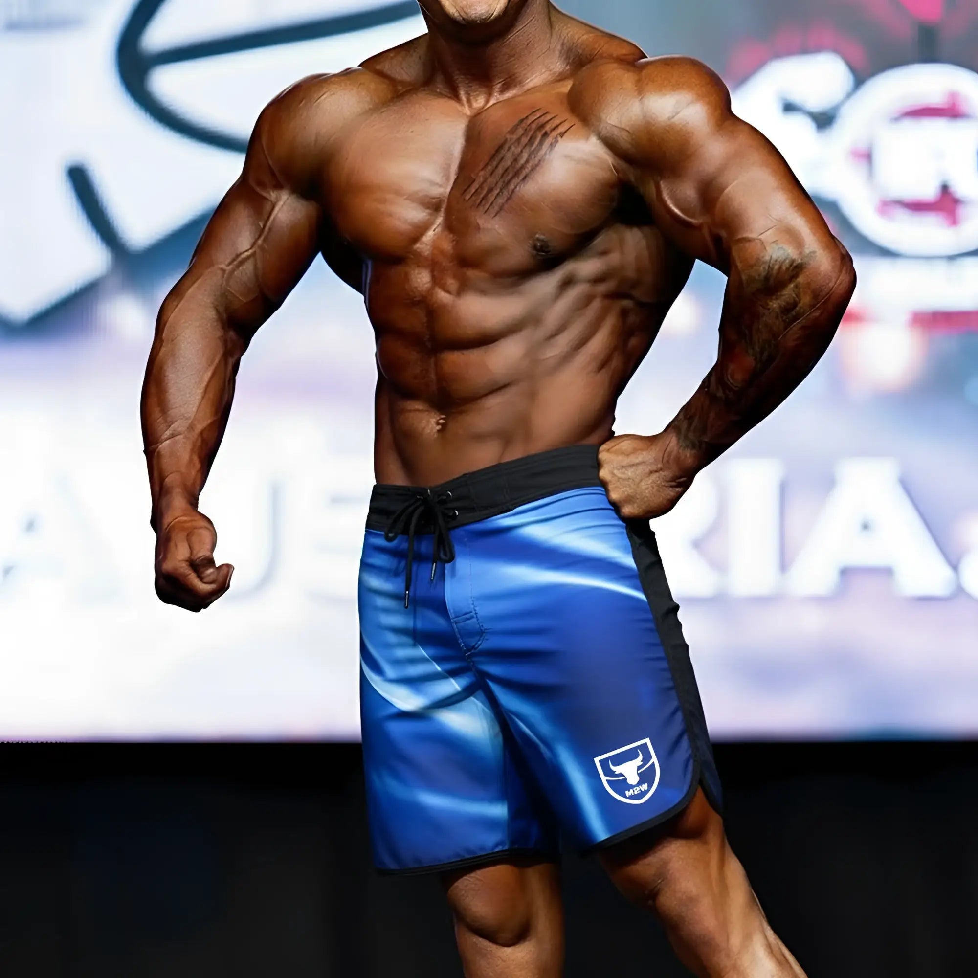 Blue metromusclewear ifbb pro mens physique board shorts with black trim and white logo on lower left leg