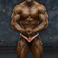 A muscular man wearing black and copper-colored MetroMaleWear MetroMuscleWear mark competition briefs